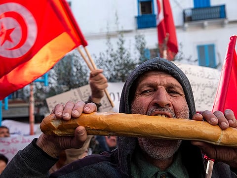 A Tunisian bites a piece of bread to protest his purchasing power during a demonstration to mark the ninth anniversary of the democratic uprising in Tunis, Tuesday, Jan.14, 2020.