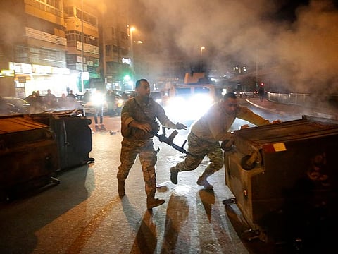 Lebanese army soldiers remove garbage containers that were set on fire by anti-government protesters to block roads in Beirut, Lebanon, Tuesday, Jan. 21, 2020.