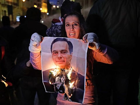 A Lebanese anti-government protester burns a picture of new prime minister Hassan Diab during a protest near the parliament headquarters in the central downtown district of the capital Beirut, on January 22, 2020.