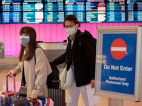 Passengers wear protective masks to protect against the spread of the Coronavirus as they arrive at the Los Angeles International Airport, California, on January 22, 2020.