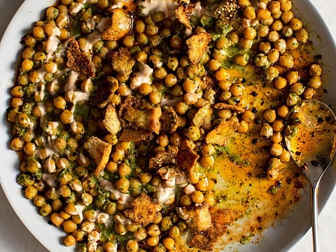 Chickpea and herb fatteh, in New York, Dec. 24, 2019. A recipe saves leftover pita bread from going to waste by layering it amid chickpeas, tahini, herbs and chile oil. (Andrew Scrivani/The New York Times)