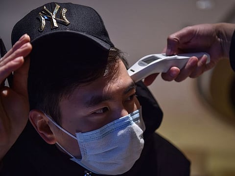 A hotel employee takes the temperature of a person that just arrived at the premise in Wuhan on January 24, 2020.