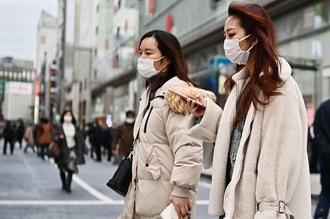 Pedestrians wearing protective masks to help stop the spread of a deadly virus which began in the Chinese city of Wuhan, walk on a street in Tokyo's Ginza area on January 25, 2020.