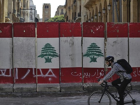 A man rides his bicycle next to a concrete wall installed by authorities to blocks a road leading to the parliament building, in downtown Beirut Friday. Arabic on the wall reads "wall of shame, left, Beirut rebels, centre, Cowards."