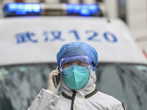 A nurse in protective gear talks on her phone near an ambulance in Wuhan in central China's Hubei Province.
