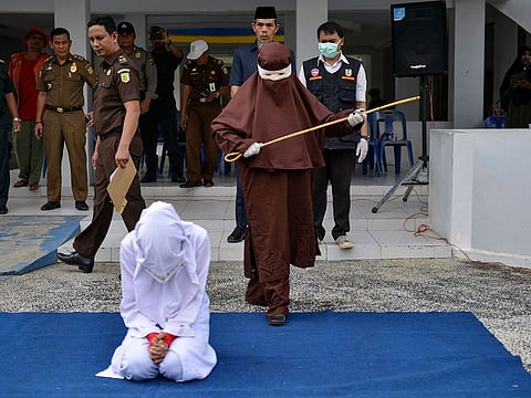 The first female flogger preparing to whip a woman in public, in Banda Aceh, after she was caught in close proximity with a man who is not her husband in a hotel.
