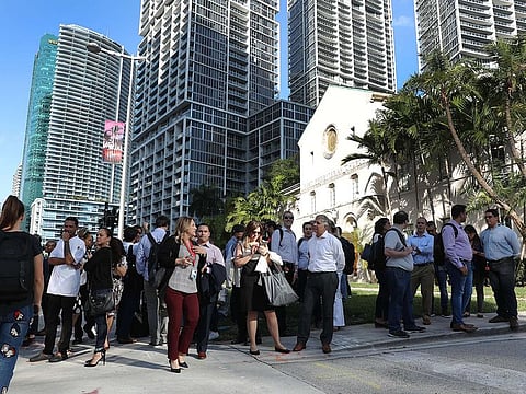 People wait outside buildings in Miami after a major 7.7 earthquake struck between Jamaica and Cuba.