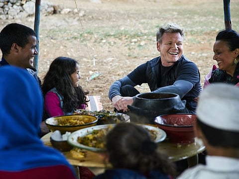Moroccan chef, Najat Kaanache (right), and Gordon Ramsay (second from right) sit with locals as they try the Moroccan New Year's Eve feast they prepared for them.