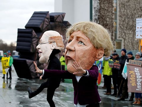 Protesters wear masks bearing German Chancellor Angela Merkel (R) and Economy Minister Peter Altmaier (L) during a demonstration gathering several environmental organisations against delayed exit from coal power on January 29, 2020 in Berlin. Bowing to public pressure on climate change, Germany on January 16, 2020 promised to speed up its exit from coal power generation and to pay operators compensation in a strategy instantly rejected by environmental campaigners.