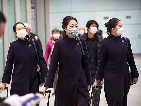 Flight crew members wearing face masks walk through the international arrivals area at Beijing Capital International Airport in Beijing, Thursday, Jan. 30, 2020.