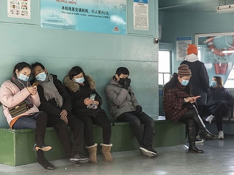 Passengers wearing protective masks browse smartphones while riding on a ferry in Shanghai, China, on January 30, 2020.