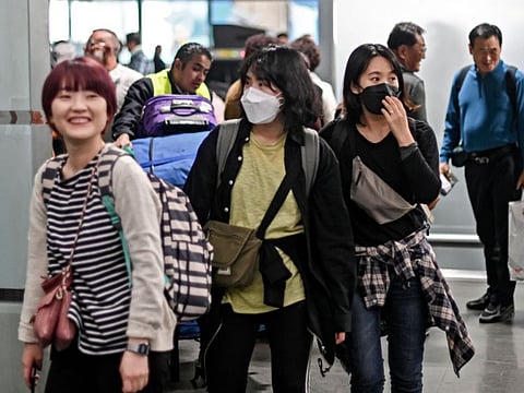 Asian women wear protective masks against the spread of coronavirus as they arrive at the Mexico City International Airport, on January 29, 2020.