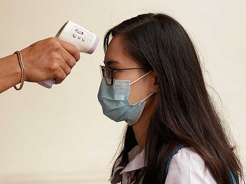 A man uses a body thermal scanner on a student wearing a protective mask as a precautionary measure against the spread of the virus at a school in Manila, Philippines, Friday, January 31, 2020.