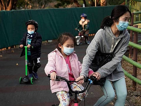 Children wearing masks, play in a park in Hong Kong, Friday, Jan. 31, 2020.