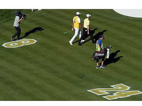 Tony Finau wears the jersey of Kobe Bryant while walking alongside Webb Simpson past a memorial on the fairway of the 16th during the final round of the Waste Management Phoenix Open golf tournament at TPC Scottsdale.