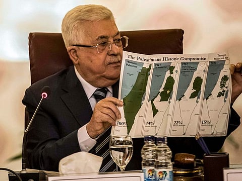 Palestinian President Mahmud Abbas displays a placard showing maps of (from left ) historical Palestine, the 1947 United Nations partition plan on Palestine, the 1948-1967 borders between the Palestinian territories and Israel, and a current map of the Palestinian territories without Israeli-annexed areas and colonies, at the Arab League emergency meeting in the Egyptian capital Cairo on February 1, 2020.