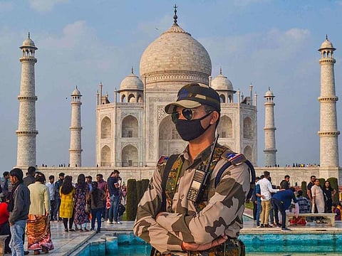 A CISF officer, wearing protective face mask, stands in the backdrop of the Taj Mahal, in Agra, Tuesday, Feb. 4, 2020.