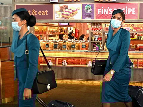 Flight attendants walk to their departure gate at Sukarno-Hatta international airport in Tangerang on February 5, 2020.