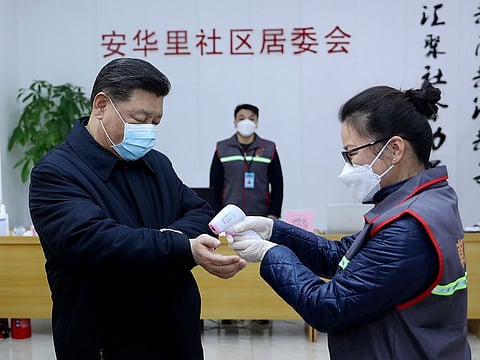 Chinese President Xi Jinping, left, wearing a protective face mask, receives a temperature check as he visits a community health center in Beijing, Monday, Feb. 10, 2020.