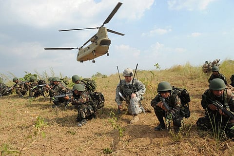 Philippine soldiers and a US Army soldier from the 2nd Stryker Brigade Combat unit of the 5th Infantry Division based in Hawaii taking their positions after disembarking from a C-47 Chinook helicopter during an air assault exercise inside the military training camp at Fort Magsaysay in Nueva Ecija province on April 20, 2015.