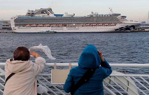 Tourists on a sightseeing cruise ship wave to passengers of the cruise ship Diamond Princess, which is anchored at Daikoku Pier Cruise Terminal in Yokohama, south of Tokyo, Japan February 12.
