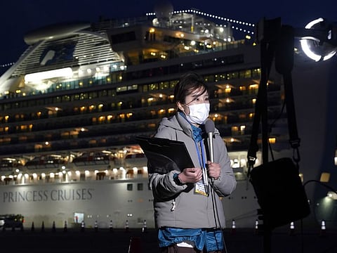 A member of the media works in front of the Diamond Princess cruise ship, sitting docked in Yokohama, Japan.