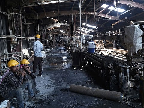 This photo taken on Sunday shows labourers sitting after fire broke out at a denim factory in Ahmedabad. Seven people died in fire incident on Saturday.