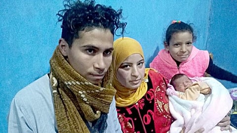 Parents of a baby girl, marking Egypt's 100 millionth, pose with her.