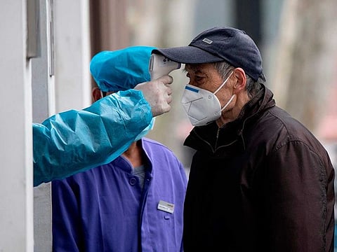 An elderly man wearing a face mask has his temperature checked before entering a community hospital in Shanghai on February 13, 2020. This picture has been used for illustrative purposes only.