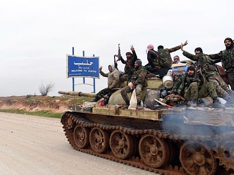 Syrian government soldiers on a tank hold up their rifles and flash victory signs, as they patrol the M5 highway that links the capital Damascus with the northern city of Aleppo.