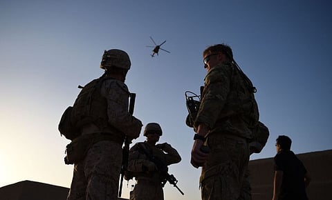 In this file photo taken in 2017 US Marines and Afghan Commandos stand together as an Afghan Air Force helicopter flies past during a combat training exercise at Shorab Military Camp in Lashkar Gah in Helmand province