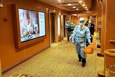 This handout photo released to AFP via Twitter handle @DAXA_TW on February 4, 2020 shows officials in masks and protective clothing on one of the decks of the Diamond Princess cruise ship, as the vessel carrying 3,711 people sits in the port of Yokohama. At least 10 people on the cruise ship quarantined off the coast of Japan have tested positive for the new coronavirus, Japan's health minister said on February 5.