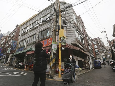 A family member poses to takes picture in front of a supermarket that appeared in South Korean director Bong Joon-ho's award-winning film "Parasite” in Seoul, South Korea, Saturday, Feb. 15, 2020.