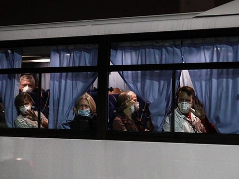 US passenger wave to reporters as they leave the Daikaku Pier Cruise Terminal in Yokohama port, next to the Diamond Princess cruise ship, with people quarantined onboard due to fears of the new COVID-19 coronavirus, at on February 17, 2020. Americans began leaving a quarantined cruise ship off Japan on February 17, 2020, to board chartered flights home as the number of new coronavirus cases diagnosed on the vessel jumped to 355. / AFP / Behrouz MEHRI