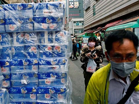 People wear masks as they walk past rolls of toilet paper at a market, following the outbreak of a new coronavirus, in Hong Kong, China February 8, 2020.