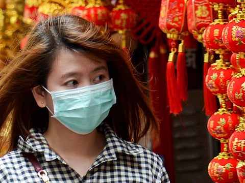 A woman wearing a face mask walks past a charms shop in the Binondo district of Chinatown in Manila. Since 1700 GMT on Sunday there were 587 new deaths reported and 11,597 new cases globally.