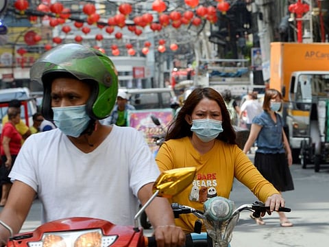 Motorists wearing face masks make their way along a street in the Binondo district of Chinatown in Manila.
