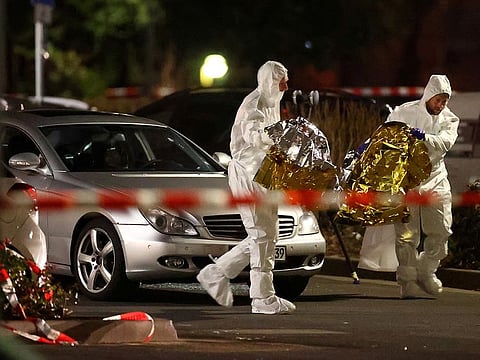 A body is seen in a damaged car as forensic experts work after a shooting in Hanau near Frankfurt