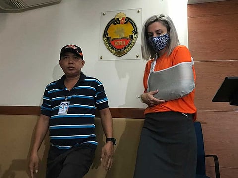 Jennifer Talbot wears a face mask as she is escorted by an agent of the National Bureau of Investigation.
