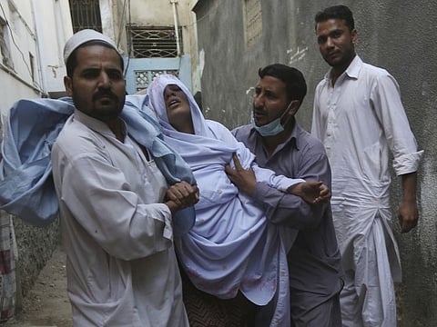 A woman who suffers from respiratory problem after a toxic gas leak, is rushed to a hospital by family members in Karachi, Pakistan, Tuesday, Feb. 18, 2020. A toxic gas leak killed five people and sickened dozens of others in a coastal residential area in Pakistan's port city of Karachi, police said Monday. The source of the leak, which occurred on Sunday night, and the type of gas that had leaked were not immediately known. On Tuesday some residents are still having breathing problems.