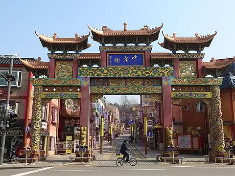 A man wearing a face mask rides a bicycle to pass the Chinatown's main entrance gate in Incheon, South Korea.