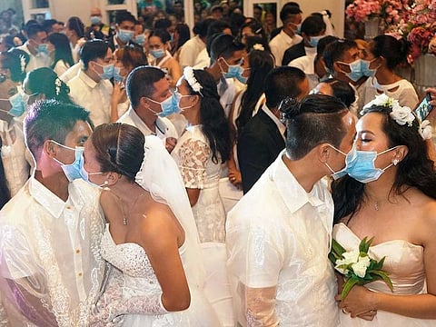 Filipino couples kiss while wearing their face masks in a government-sponsored mass wedding in Bacolod City, Philippines, February 20, 2020.