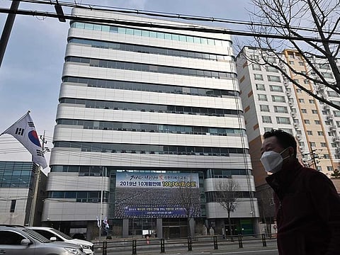 A man wearing a face mask walks in front of the Daegu branch of the Shincheonji Church of Jesus in the southeastern city of Daegu on February 21, 2020 as more than 80 members of Shincheonji have now been infected with the COVID-19 coronavirus.