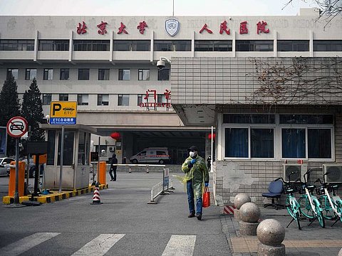 A man wears protective clothing as a preventive measure against the COVID-19 coronavirus as he walks outside the Peking University People's Hospital in Beijing on February 21, 2020.