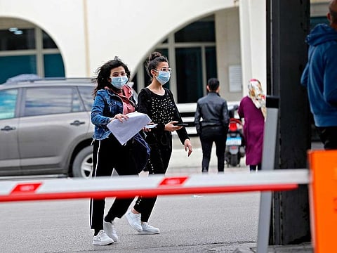 Young women wearing protective masks walk out of the Rafik Hariri University Hospital in the southern outskirts of the Lebanese capital Beirut on February 21, 2020, where a woman is treated for coronavirus, the first case in the country.