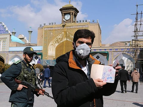 An Iranian voter wears a mask and shows his ID during parliamentary elections at the Shah Abdul Azim shrine on the southern outskirts of Tehran on February 21, 2020. Iran's health ministry today reported two more deaths among 13 new cases of coronavirus in Iran, bringing the total number of deaths to four and infections to 18.