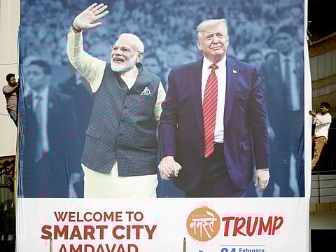 A worker installs a hoarding with the images of the US President Donald Trump and India's Prime Minister Narendra Modi, ahead of Trump's visit to India, in Ahmedabad on Friday.