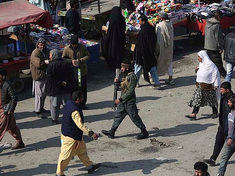 A security police officer, center, walks through a busy bazaar in Kabul, Afghanistan on February 22, 2020. A temporary truce between the United States and the Taliban took effect on Friday, setting the stage for the two sides to sign a peace deal next week aimed at ending 18 years of war in Afghanistan and bringing US troops home.