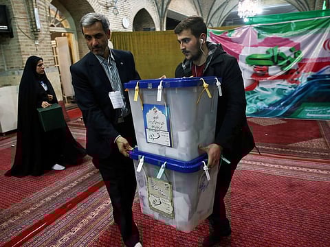 Poll workers carry full ballot boxes after the parliamentary election voting time ended in Tehran on Saturday.