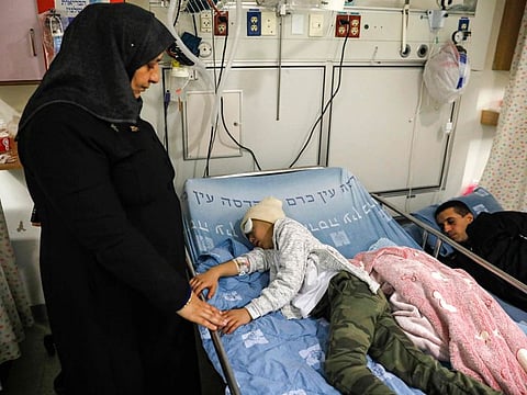 Malik Eisa, a nine-year-old Palestinian boy, lies on a bed as his father sleeps nearby and a relative stands above him, at Hadassa Ein Karem hospital in occupied Jerusalem on February 20 days after he was shot in the face by Israeli occupation police.